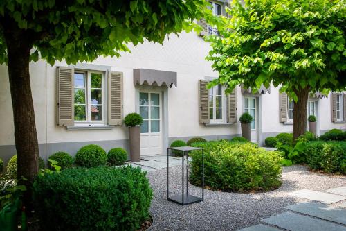 ein weißes Haus mit Bäumen und Büschen davor in der Unterkunft Relais San Vigilio al Castello in Bergamo