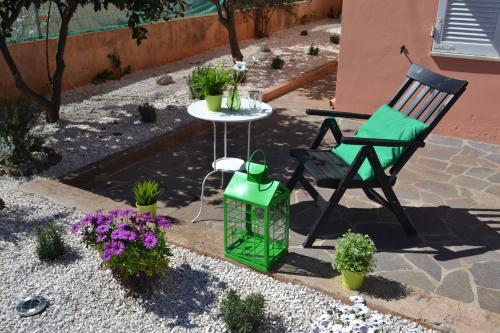 een patio met een stoel, een tafel en bloemen bij Casa Vacanze Mura in Cala Gonone