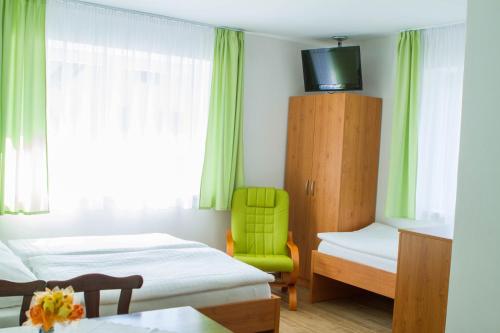 a room with two beds and a green chair at Vila Sofia in Luhačovice