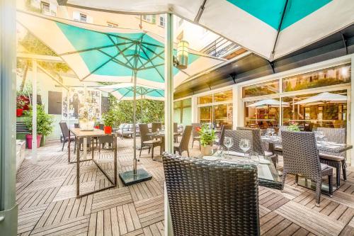 ein Restaurant mit Tischen, Stühlen und Sonnenschirmen in der Unterkunft Hôtel Montaigne & Spa in Cannes