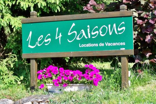 un cartel verde con flores rosas en un jardín en Gîte Les 4 Saisons, en Orbey