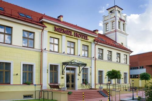 a large yellow building with a clock tower on top at Memel Hotel in Klaipėda