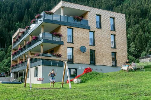 Dziewczyna bawi się na placu zabaw przed budynkiem w obiekcie Appartements Ausblick w mieście St. Gallenkirch