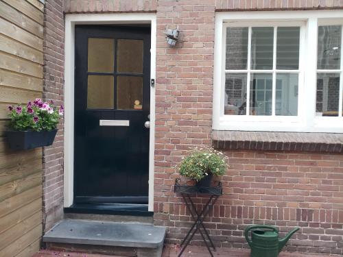 een zwarte deur op een bakstenen huis met twee potplanten bij B&B de Notaris in Assen