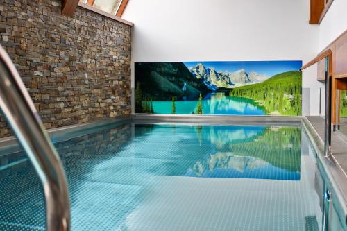 a swimming pool in a house with a tv on the wall at Hotel Bystra in Białka Tatrzanska