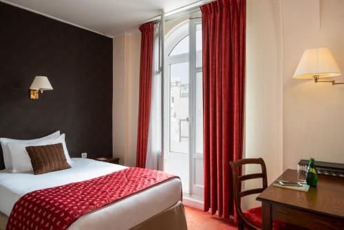 ein Hotelzimmer mit einem Bett, einem Schreibtisch und einem Fenster in der Unterkunft Abaca Messidor by Happyculture in Paris