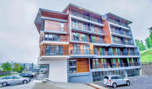 Un grand bâtiment avec des voitures garées devant lui dans l'établissement Area Park Bakuriani, à Bakuriani