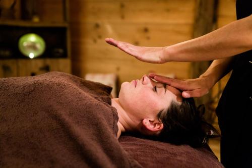 een vrouw die een hoofdmassage krijgt van een therapeut bij Chalet-Hôtel La Marmotte, La Tapiaz & SPA, The Originals Relais in Les Gets