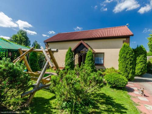 une maison avec un toit rouge et une cour dans l'établissement Domek nad Kanałem Łuczańskim, à Giżycko