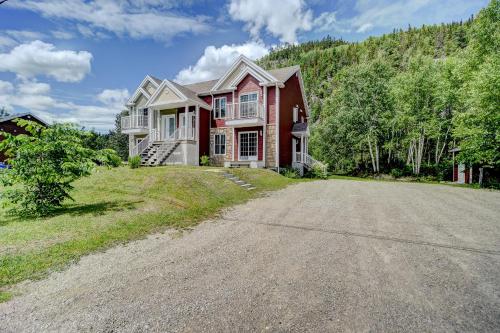 una gran casa roja en una colina con entrada en Entre roc et montagne, en L'Anse-Saint-Jean