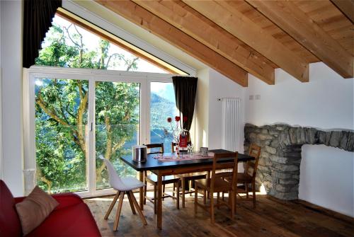 uma sala de jantar com uma mesa e uma grande janela em Foresteria B&B Vecchiascuola Pianazzola em Chiavenna