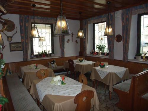 una sala da pranzo con tavoli, sedie e finestre di Gasthof Alte Post a Obertrubach