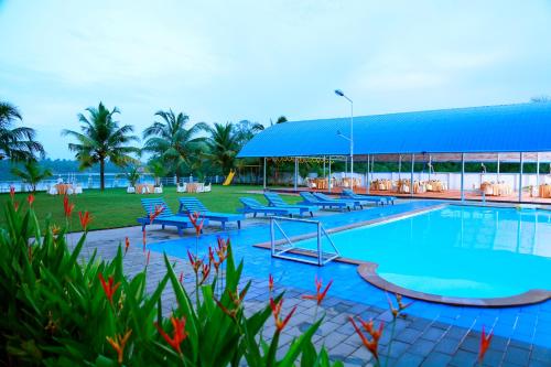 een groot zwembad met stoelen en een gebouw bij Blue Waters Cherai in Cherai Beach