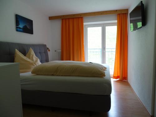 a bedroom with a bed and a window with orange curtains at Apart Tyrol in Umhausen