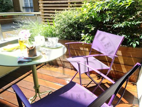 two purple chairs and a table on a patio at Hotel Boileau in Paris