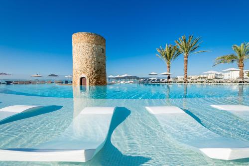 ein Pool mit Stühlen und ein Turm im Wasser in der Unterkunft Hotel Torre del Mar - Ibiza in Playa d'en Bossa