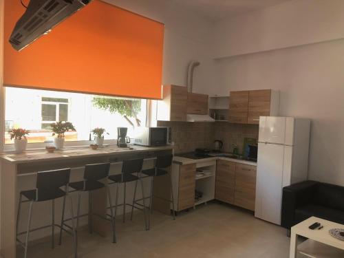 cocina con nevera blanca y taburetes en Sisifou Hostel, en Korinthos