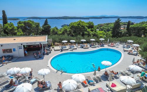 uma vista superior para uma piscina com cadeiras e guarda-sóis em Pharos Hvar Hotel em Hvar