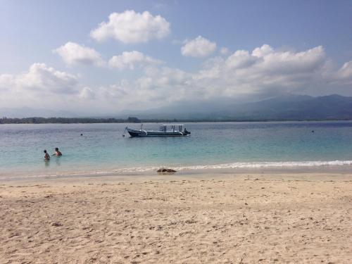 un barco en el agua en una playa en Blu d'aMare, en Gili Trawangan