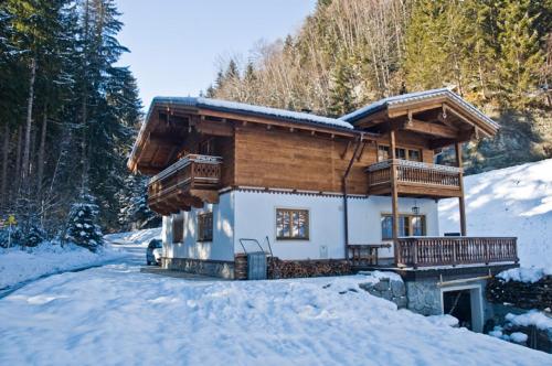 une cabane en rondins dans la neige dans les bois dans l'établissement Ferienwohnung Steiner, à Wald im Pinzgau