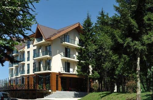 un grand bâtiment avec des arbres devant lui dans l'établissement AuRoom Bakuriani Resort, à Bakuriani