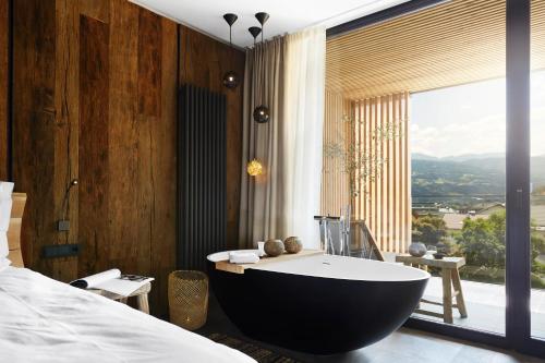 a bedroom with a bath tub and a bed and a window at Hotel Löwenhof in Bressanone