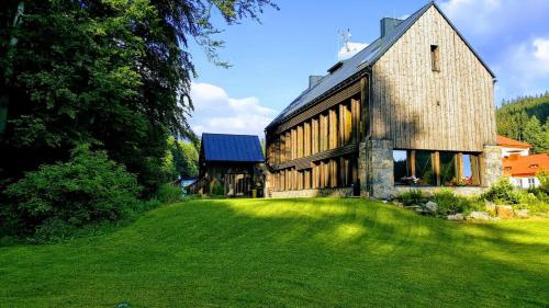 un grande edificio in pietra con un prato di Krakonošova Dílna "WOODHAUS" a Špindlerův Mlýn