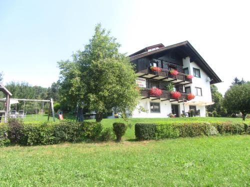 a house with red flowers on the balconies on a field at Erlebnishaus Spiess in Feldkirchen in Kärnten