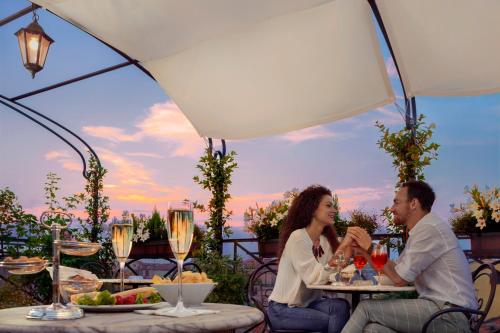 un homme et une femme assis à une table avec des verres à vin dans l'établissement Hotel Firenze, à Venise