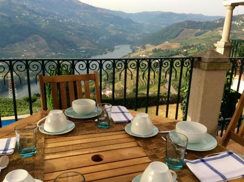 a table with plates and cups on a table with a view at Casa De Canilhas in Mesão Frio