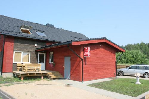 una pequeña casa roja con un coche aparcado delante en Love Island Guesthouse, en Druskininkai