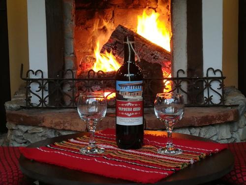 a bottle of wine and two glasses on a table in front of a fireplace at Once upon a time in Koprivshtitsa