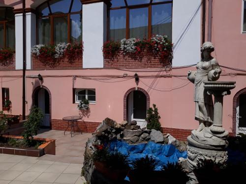 una statua di fronte a un edificio rosa con una fontana di Pensiunea Casa Rusu a Baia Mare