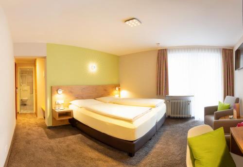 een hotelkamer met een groot bed en een stoel bij Hotel Azenberg in Stuttgart