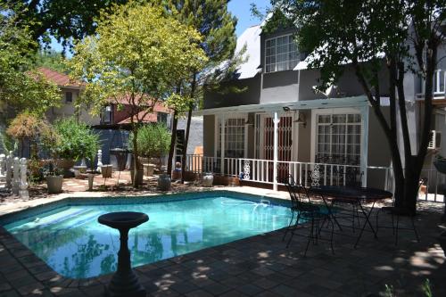 een zwembad met stoelen en een huis bij Hobbit Boutique Hotel in Bloemfontein