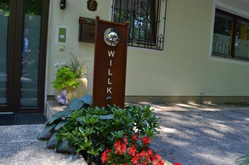 una señal de bienvenida frente a un edificio con flores en Gästehaus Pfisterer, en Bad Schallerbach