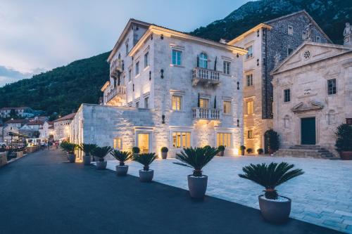 een groot gebouw met potplanten ervoor bij Heritage Grand Perast By Rixos in Perast