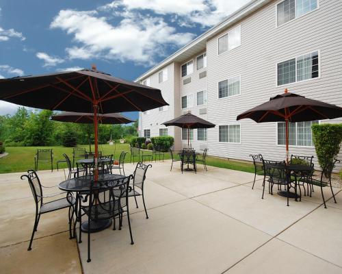 un patio con tavoli, sedie e ombrelloni di Hawthorn Extended Stay by Wyndham Oak Creek a Milwaukee