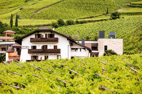 a white house in the middle of a vineyard at Pension Hasslhof in Caldaro