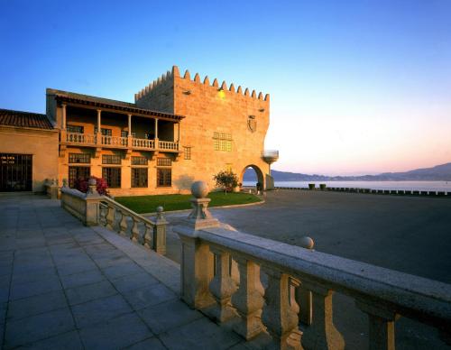 un grand bâtiment avec une clôture devant lui dans l'établissement Parador de Baiona, à Baiona