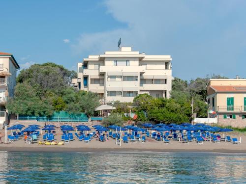 plaża z leżakami i parasolami oraz budynek w obiekcie Hotel Villa Lo Scoglietto w mieście San Vincenzo