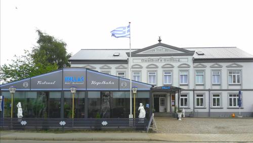 un gran edificio blanco con una bandera delante de él en Hotel Restaurant Hellas, en Gelting