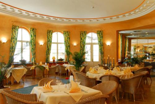 a dining room with tables and chairs and windows at Kurhotel Fürstenhof by David in Blankenburg