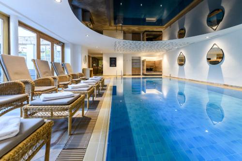 una piscina de hotel con sillas y una piscina en Hotel Staudacherhof History & Lifestyle, en Garmisch-Partenkirchen