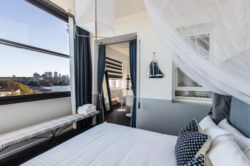 een slaapkamer met een bed en een groot raam bij Hotel Palisade in Sydney