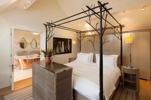 a bedroom with a canopy bed with a bath tub at Coworth Park - Dorchester Collection in Ascot