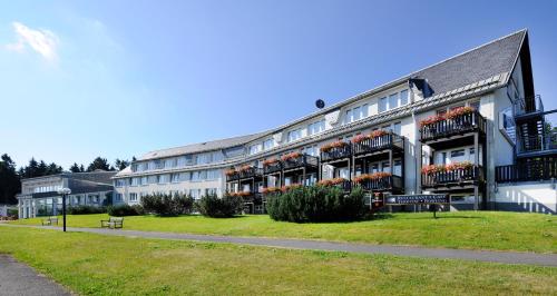 ein großes weißes Gebäude mit Blumen auf den Balkonen in der Unterkunft WAGNERS Sporthotel Oberhof in Oberhof