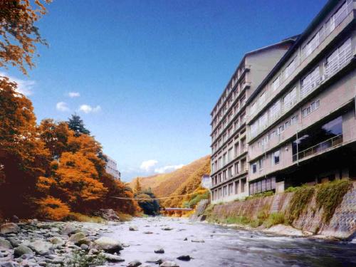 ein Fluss neben einem Gebäude neben einem Gebäude in der Unterkunft Itoen Hotel Iizakakanouya in Fukushima