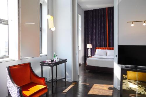 Camera con letto, sedia e TV di Hotel St Paul, Montreal, a Member of Design Hotels a Montréal