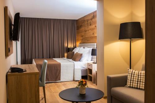 a hotel room with a bed and a couch and a table at Korona, Resort & Entertainment in Kranjska Gora